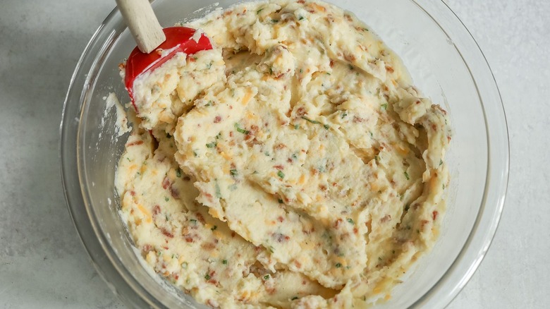 Loaded mashed potatoes in bowl with rubber spatula