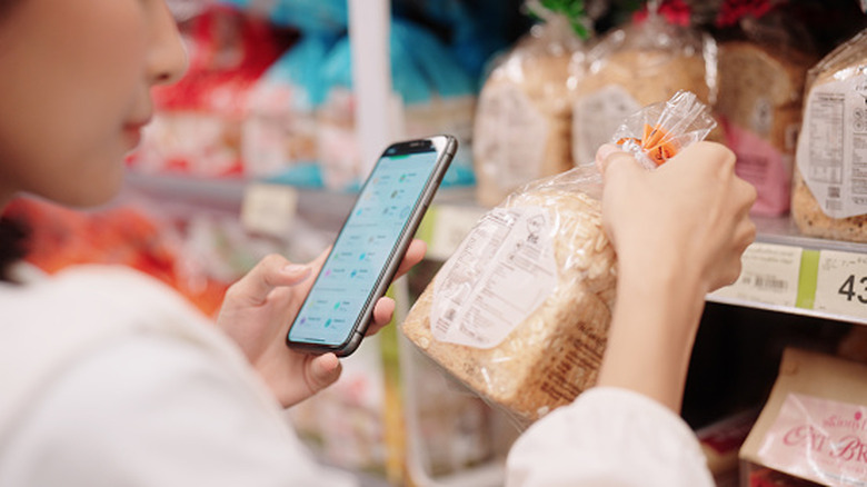 Person checks the ingredients label on a loaf of bread at the supermarket