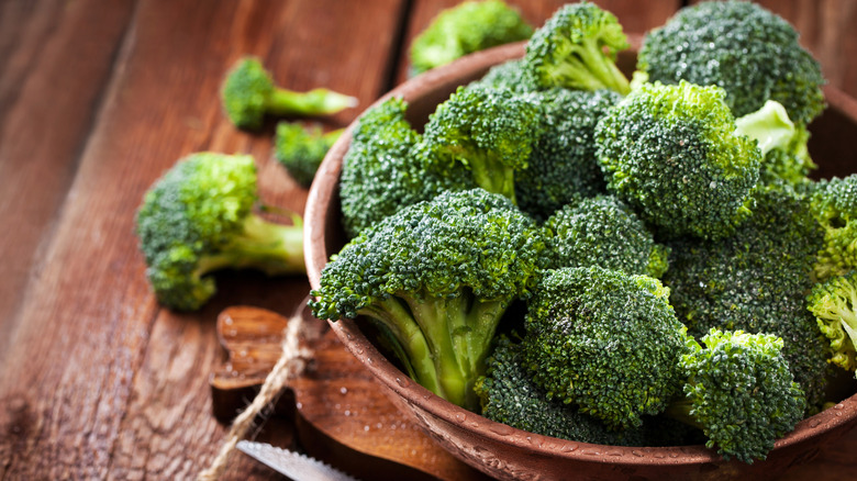 Fresh, green broccoli in a bowl over a wooden table.