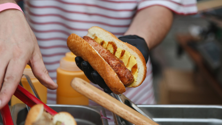 Vendor at a hot dog cart making food for a customer