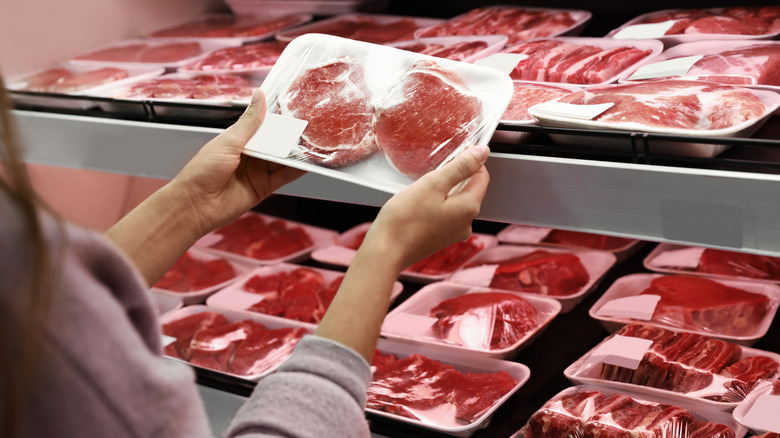 A woman purchasing beef at the grocery store