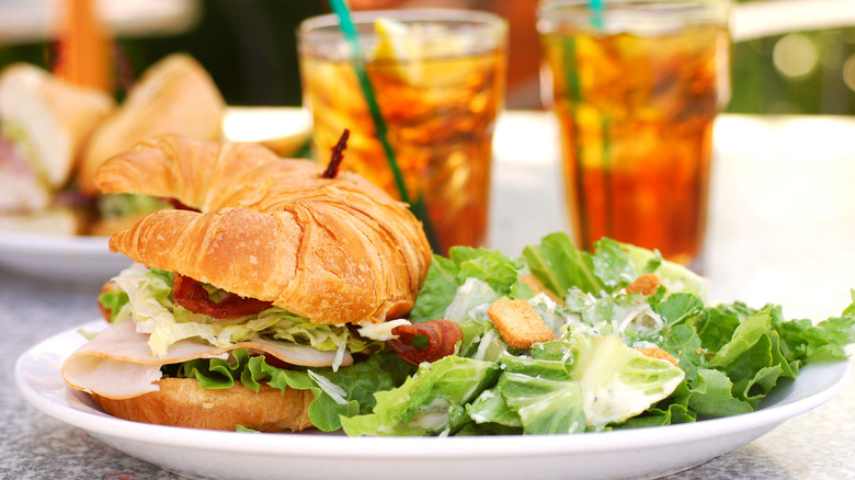 croissant sandwich and side salad on plate