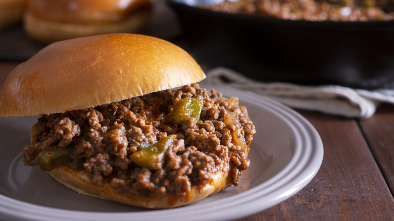 A sloppy joe sits on a glass plate.