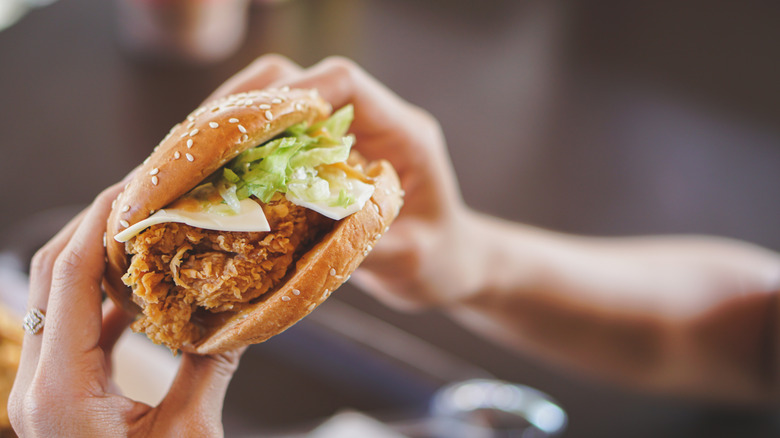 person eating chicken sandwich in a restaurant