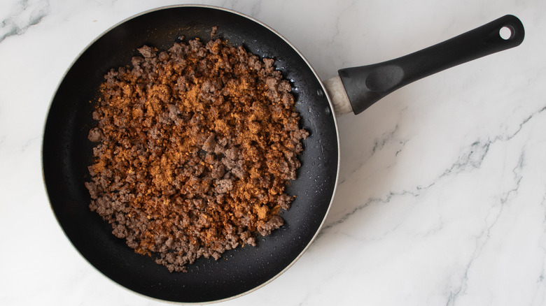 cooked ground beef in a black frying pan