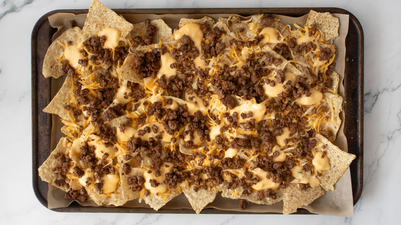 tortilla chips, beef, and cheese in a baking pan