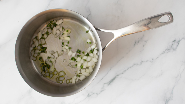 chopped onions and peppers in a metal pot