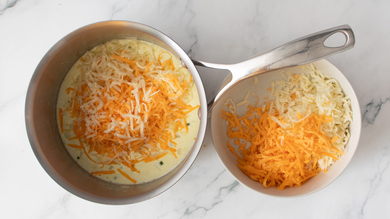 shredded cheese and white liquid in a metal pot