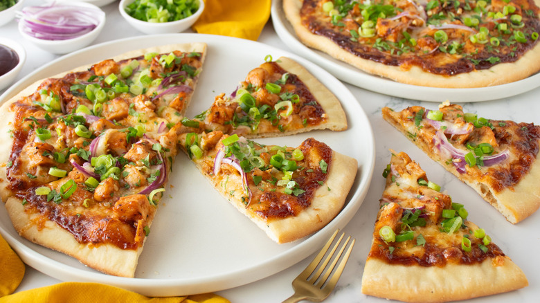 two pizzas topped with chicken and green onions