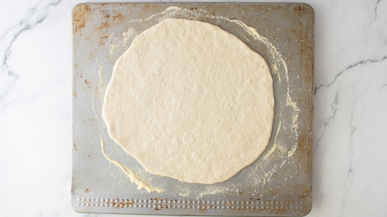 unbaked pizza crust on a sheet pan