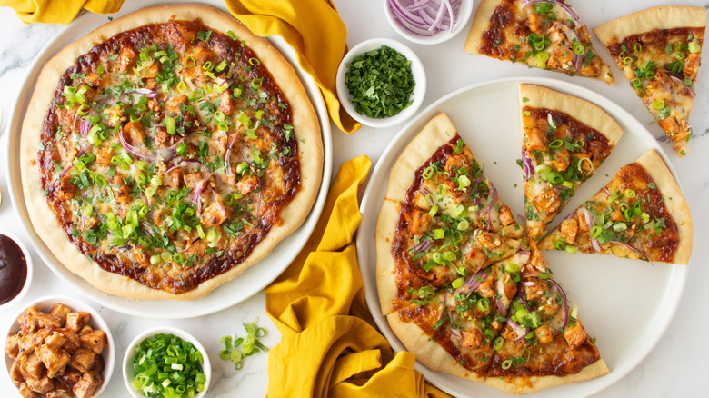 two pizzas topped with chicken and green onions