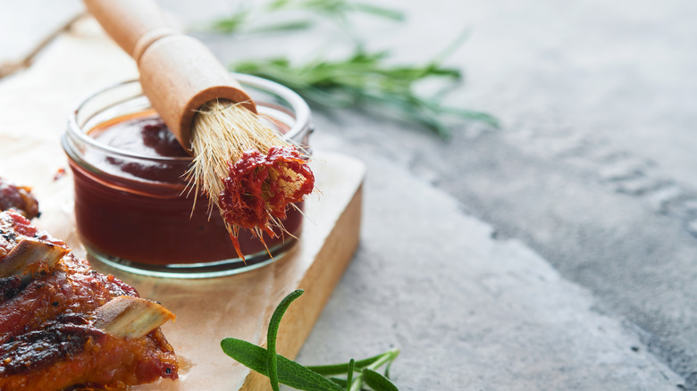 Hot and spicy barbecue sauce in a glass bowl with a basting brush