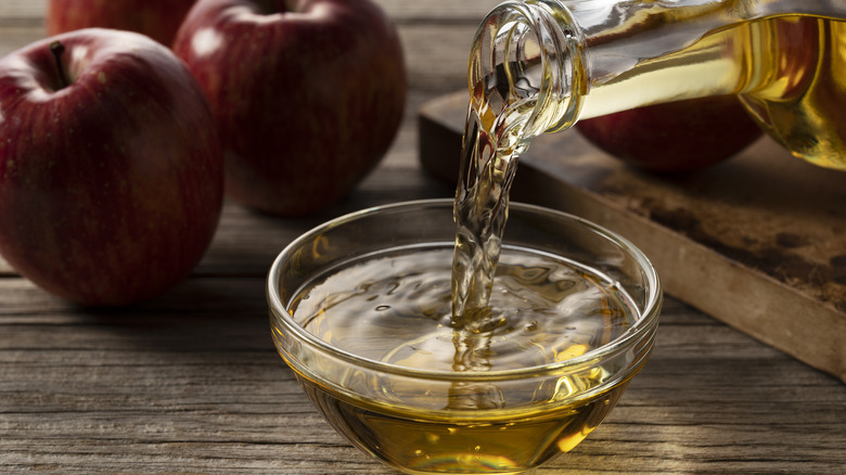 Apple cider vinegar being poured into a glass container