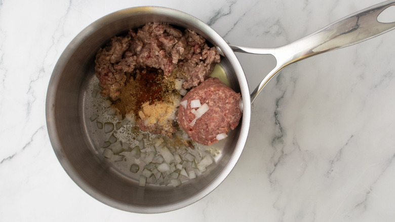 Ground beef, ground sausage, onion, and seasonings in saucepan