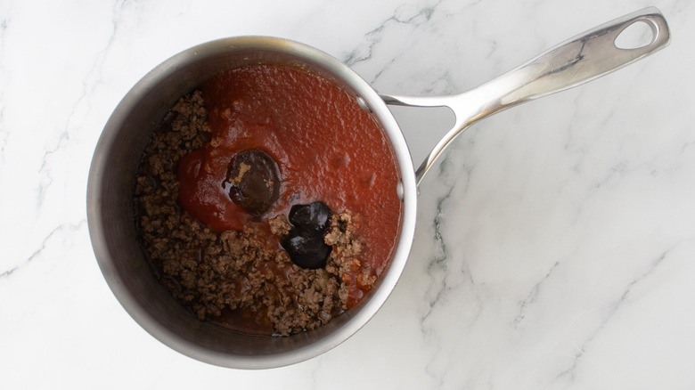 Unmixed chili ingredients in saucepan on marble surface