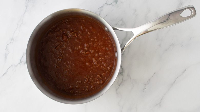 Aerial view of cooked chili in saucepan on marble surface