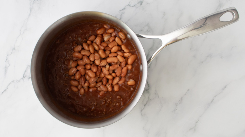 Pinto beans in chili in saucepan on marble surface