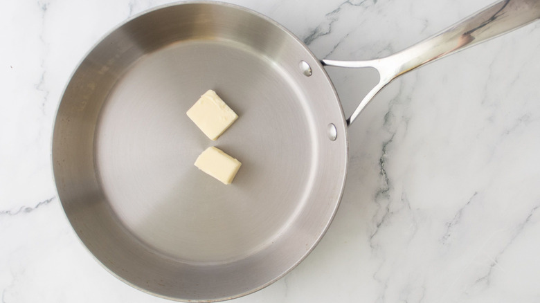 Pats of butter in a clean stainless steel skillet
