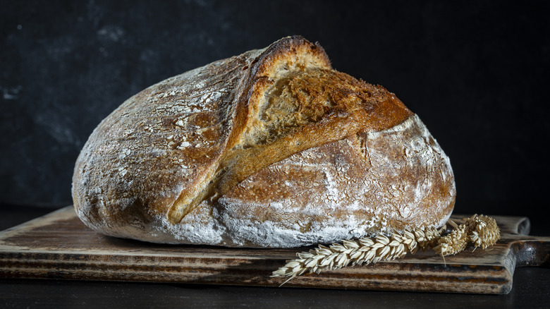 A crispy loaf of fresh-baked sourdough bread on a cutting board