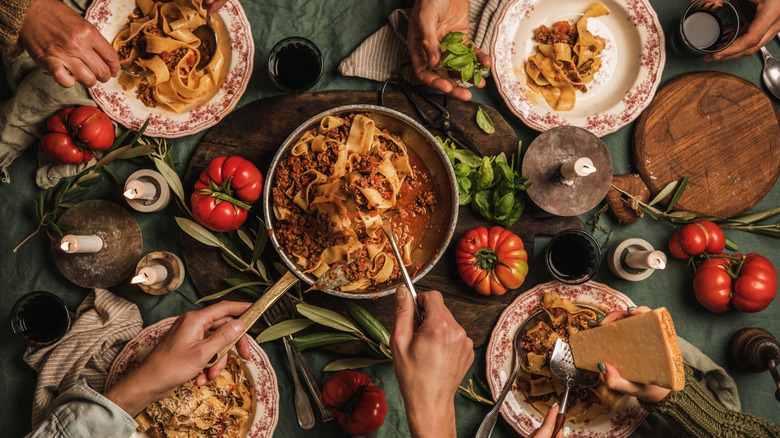 Dinner table with pasta Bolognese in pot and on plates. 