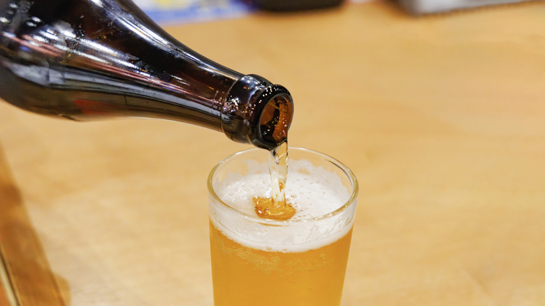 Beer pouring from brown bottle into glass.