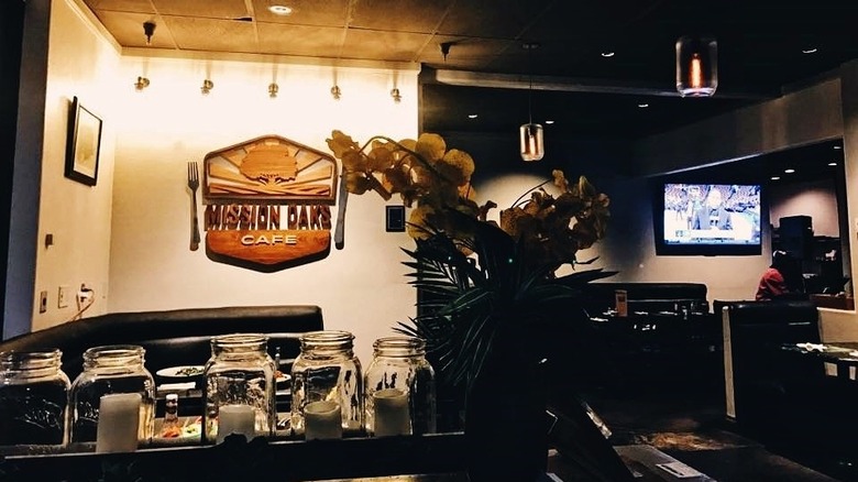 The interior of a restaurant with a sign on the wall for Mission Oaks Cafe and a TV on the right side