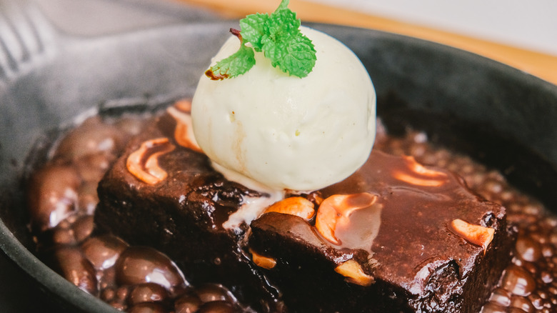 Vanilla ice cream with chocolate sauce, nuts and a chocolate brownie