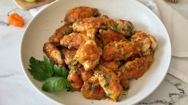 Mango habanero chicken wings in bowl garnished with chopped herbs