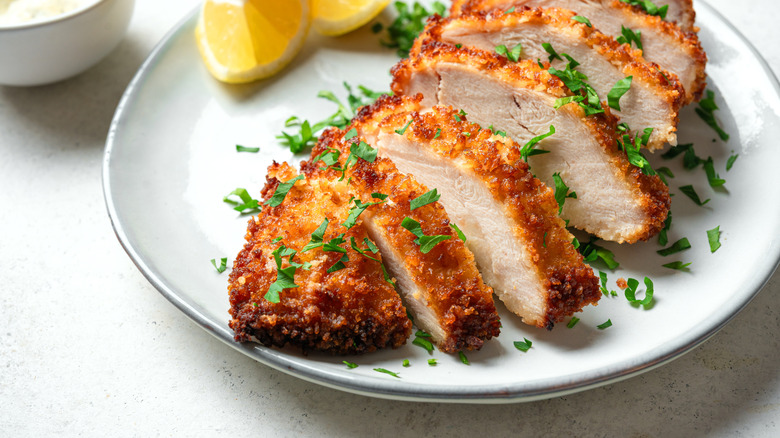 Breaded chicken sliced up on white plate