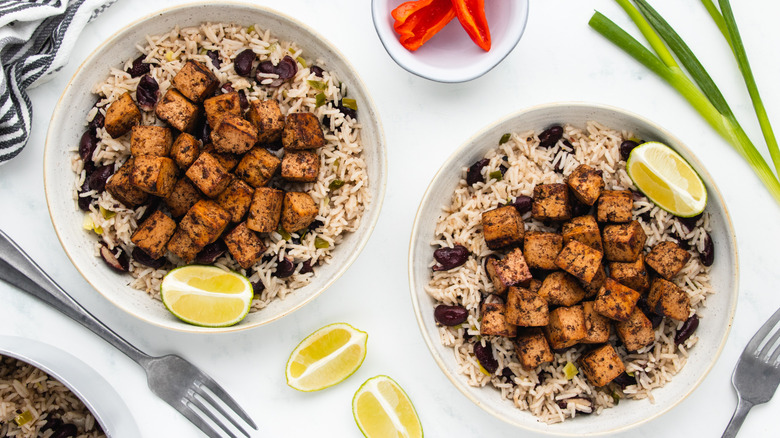 Two bowls of jerk tofu with rice and peas