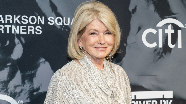 Martha Stewart smiling at a press appearance wearing a sequin jacket and dangling earings