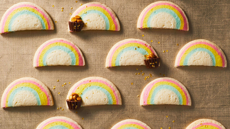 Half-moon-shaped cookies with blue, yellow, and pink stripes on brown dish towel