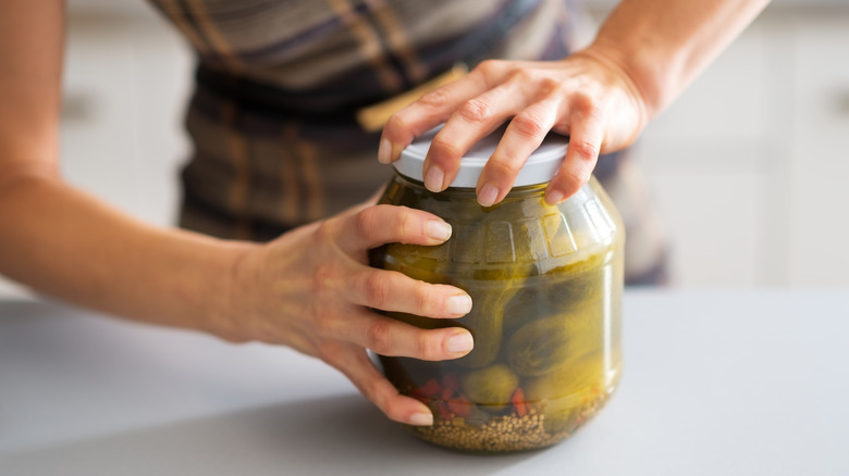 woman opening a pickle jar