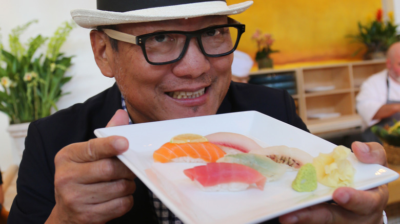 Chef Morimoto holding up a plate of nigiri sushi