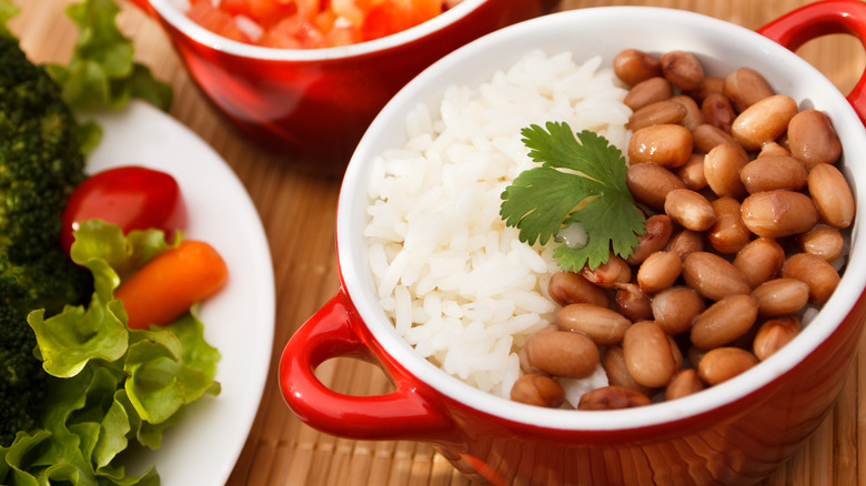 rice and beans in a small bowl with salad and salsa in the background