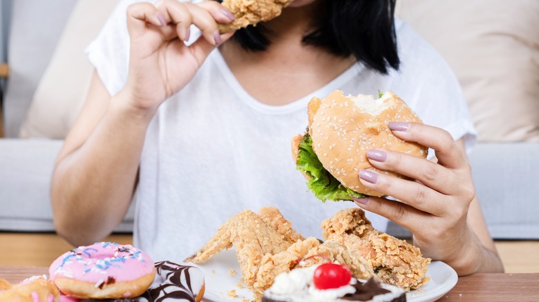 woman eating chicken and sandwich