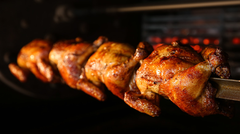 Rotisserie chickens roasting on a spit