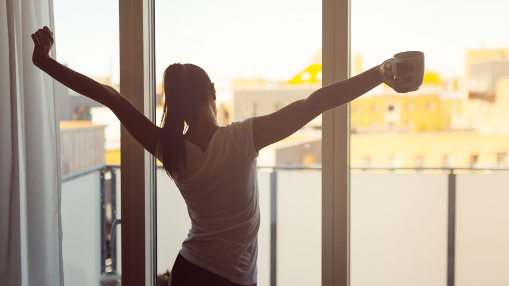 Woman stretching with cup of coffee 