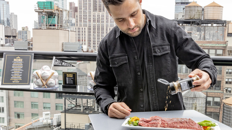 Max Greb seasoning meat on balcony