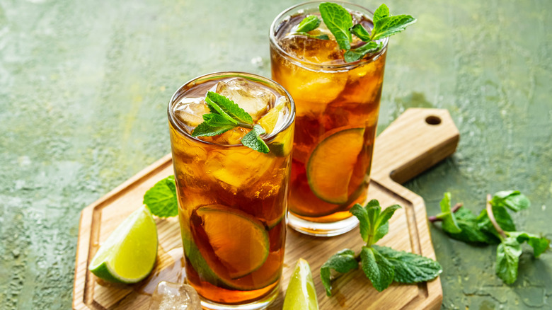 Glasses of iced tea on a wood board with lime wedges