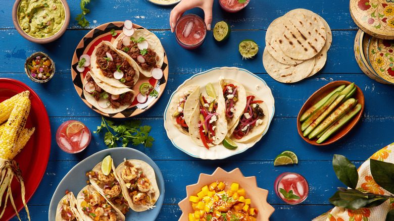 Variety of tacos and salsas on a blue table