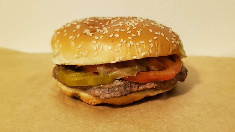 Close up of a Whopper from Burger King with patty, pickles, tomatoes on sesame seed bun