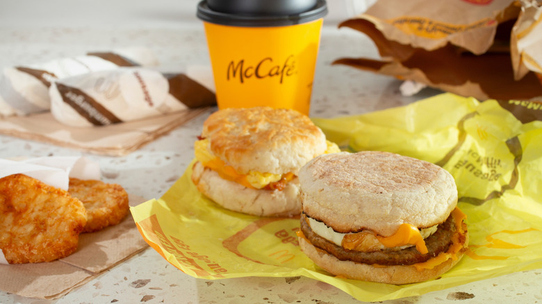 Assorted breakfast sandwiches, hash browns, and coffee on table at McDonald's restaurant.