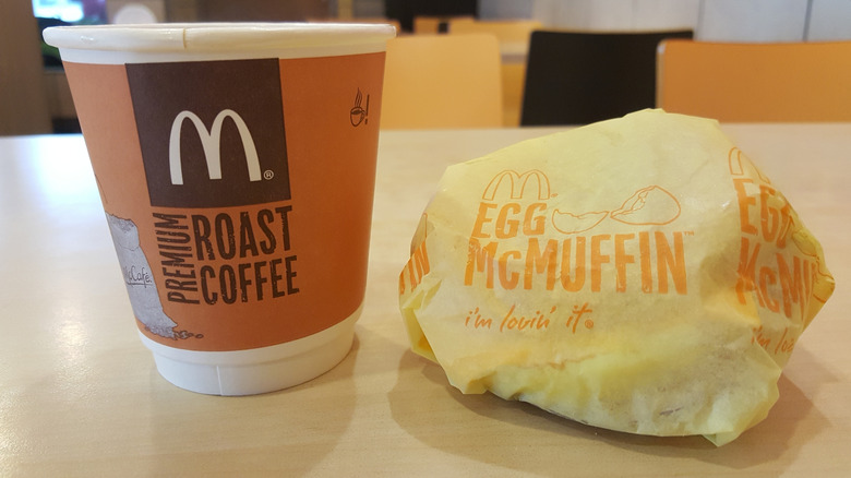McDonald's egg McMuffin and cup of coffee on table inside the restaurant.
