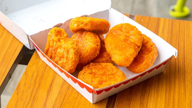 An open box of McDonald's chicken McNuggets on a wooden table.