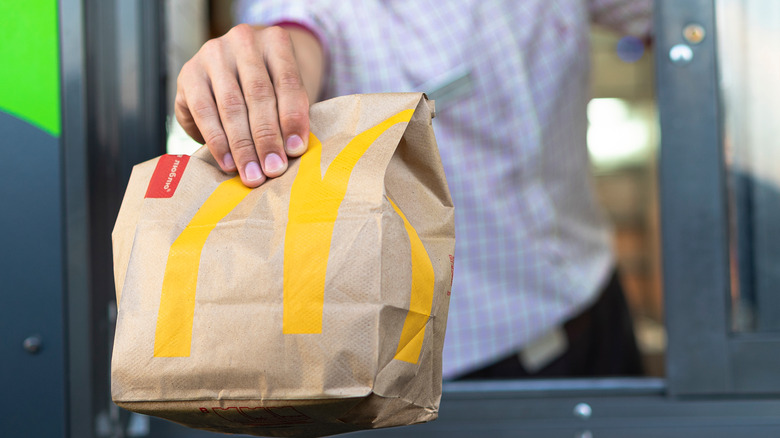 Employee at drive-thru handing customer a bag