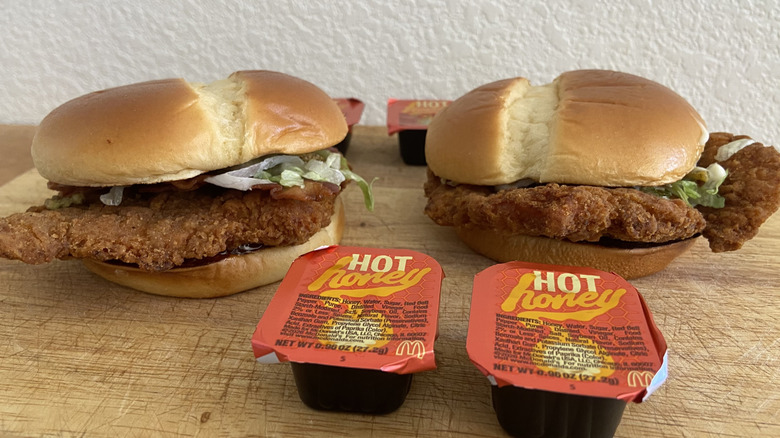 both sandwiches amidst four sauce cups on cutting board