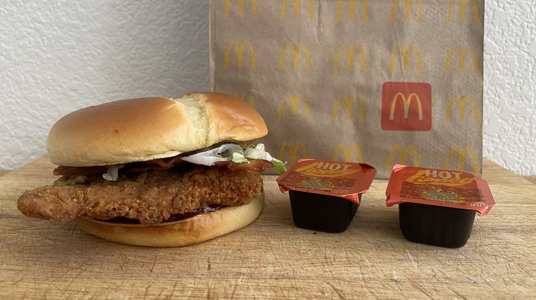 Bacon Hot Honey McCrispy on a cutting board two sauces cup and a McDonald's bag