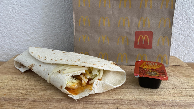 Hot Honey Snack Wrap on a cutting board with sauce cup and a McDonald's bag