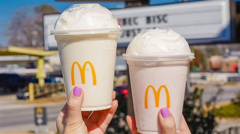 Person holding two McDonald's milkshakes